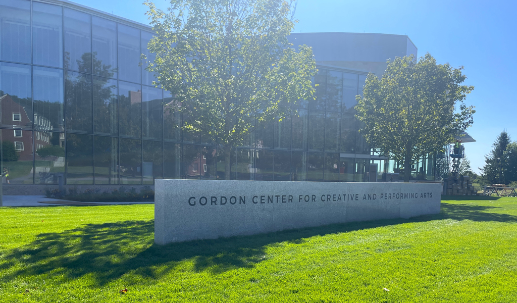 A glass building with a cement monument sign in front.