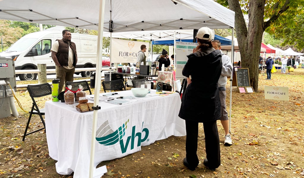 A VHB table under a popup tent a National Night out with a woman in a black coat and glasses speaking to an older woman in a blue coat about changes they would like to see in Haverhill.