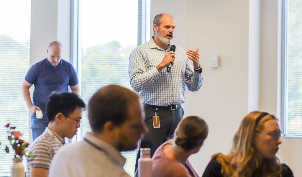 Kevin Fischer speaks into the microphone addressing the audience at a VHB event.