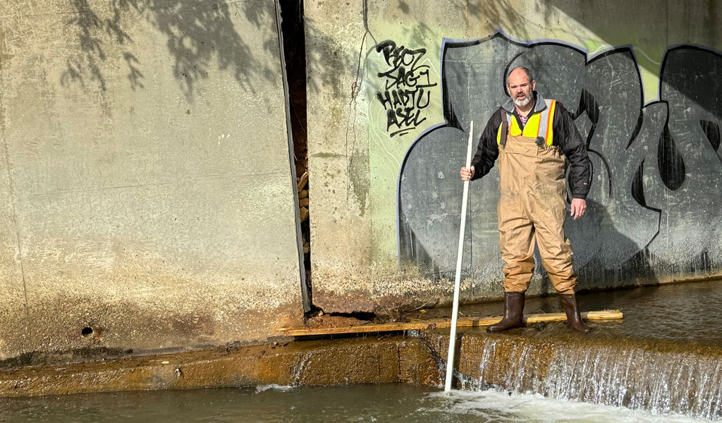 Kevin Fischer stands underneath a bridge with waders on during the aftermath of Hurricane Helene in Western North Carolina.