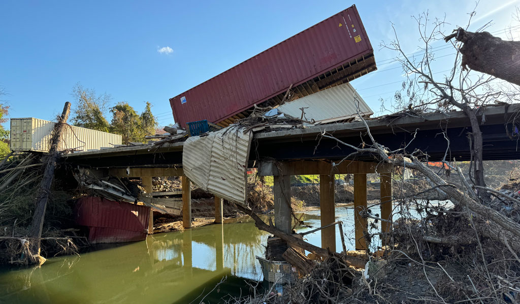 Washed shipping containers sit on a severely damaged bridge after Hurricane Helene.  