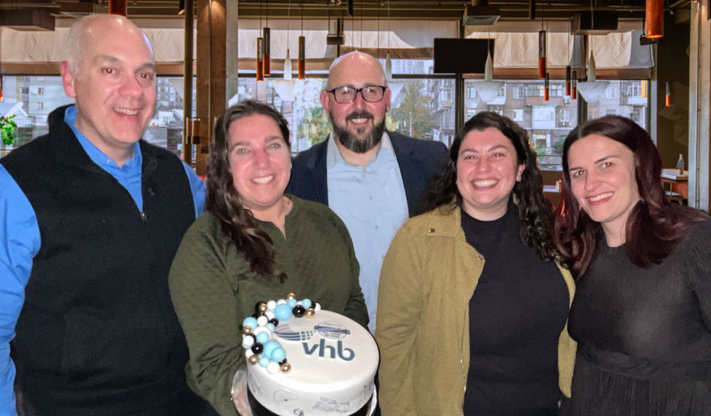 VHB employees holding a cake. 