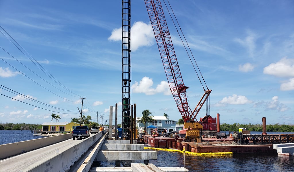 A crane in the water near a bridge.