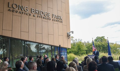 Secretary of Transportation, Pete Buttigieg, stands at the podium to give a speech at the Long Bridge Aquatics Center.