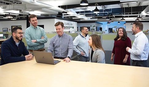 Group of VHBers at a work station with a laptop.