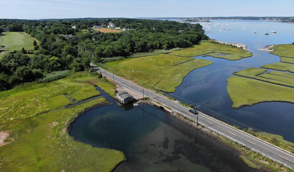 A low roadway with a small bridge underneath and water on both sides.