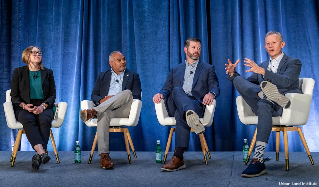 Four panelists sitting on a stage engaged in a discussion at a conference.