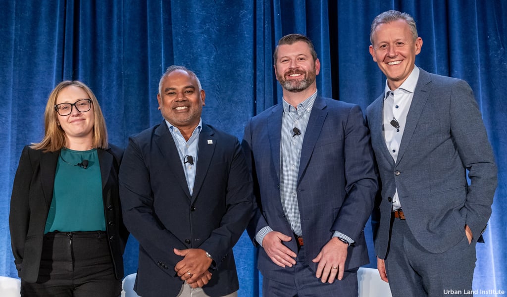 Four panelists posing for a team photo after a panel discussion at a conference.