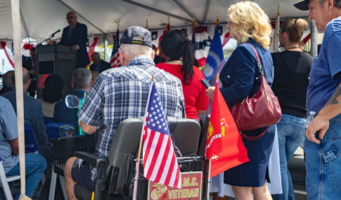 A Veteran listens to a speaker who is at a podium.