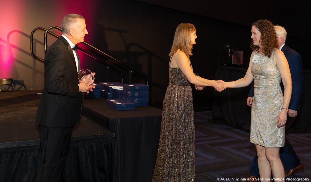 Lauren Blackburn shakes hands on stage and accepts the Virginia ACEC award.