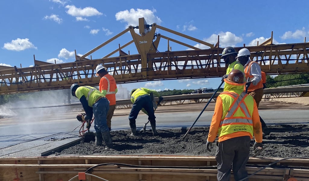 Seven men on a highway construction site pouring concrete