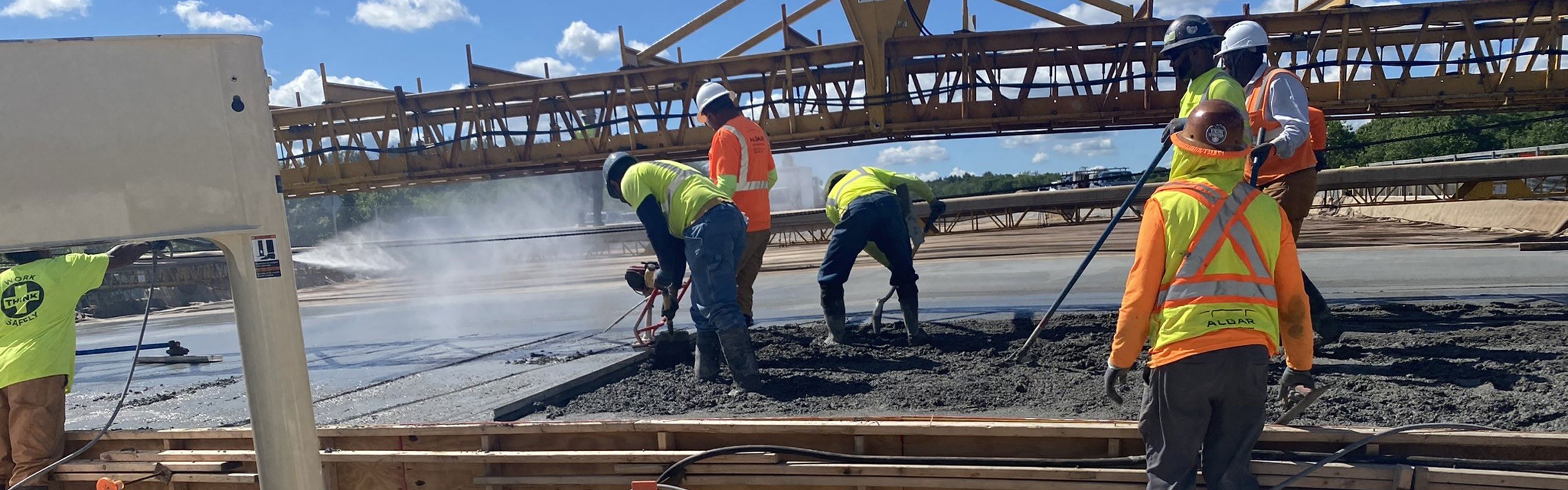 Seven men on a highway construction site pouring concrete