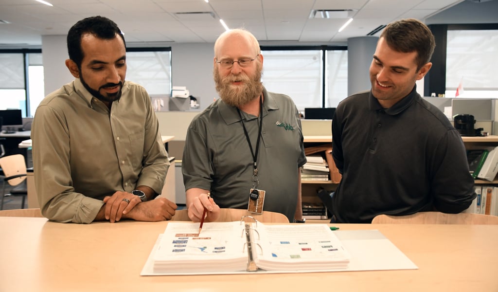 From left to right: Ahmed Amer, Michael Tantillo, and Christian Harar referencing the Community Wayfinding sign standards in the MUTCD. 