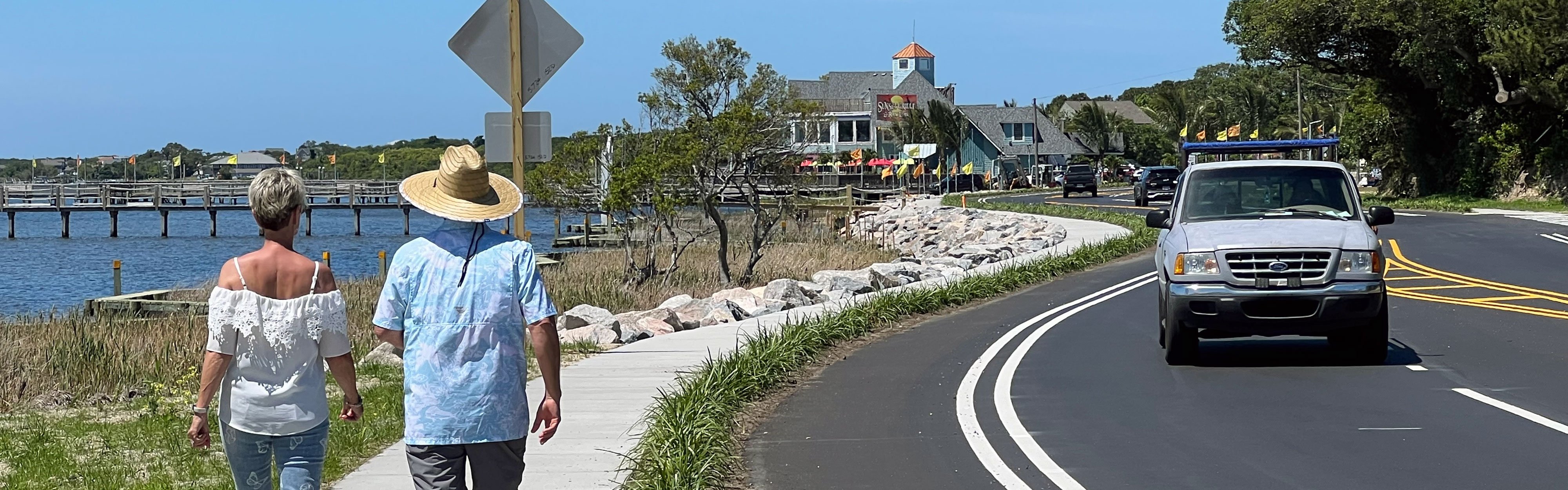 Two people walk along the new sidewalk at the completion of the project.