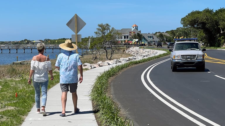 Two people walk along the new sidewalk at the completion of the project. 