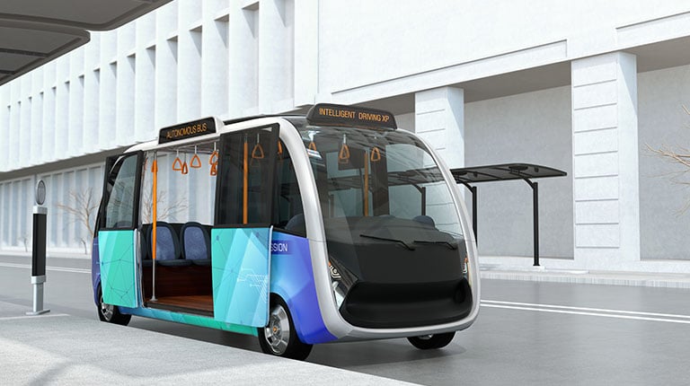 Self-driving shuttle bus waiting at bus station. The bus station equipped with solar panels for electric power.