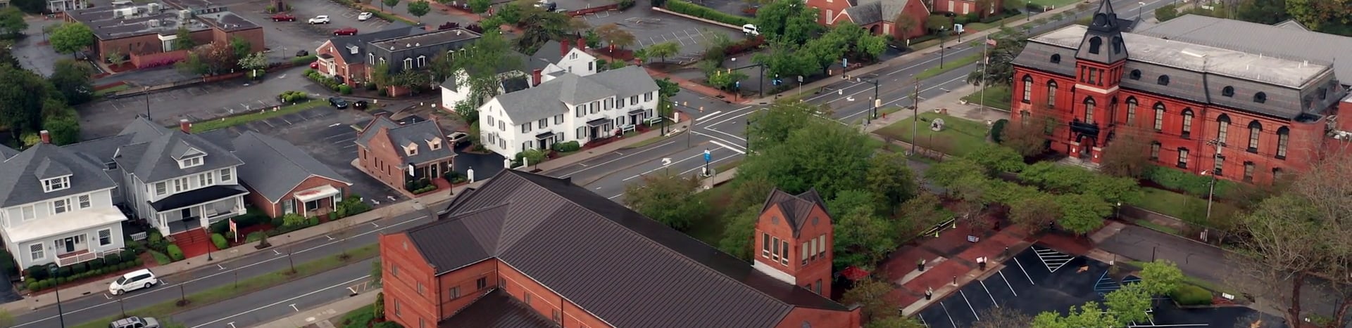 An aerial view of the downtown area of New Bern, NC, with green space and many brick buildings.