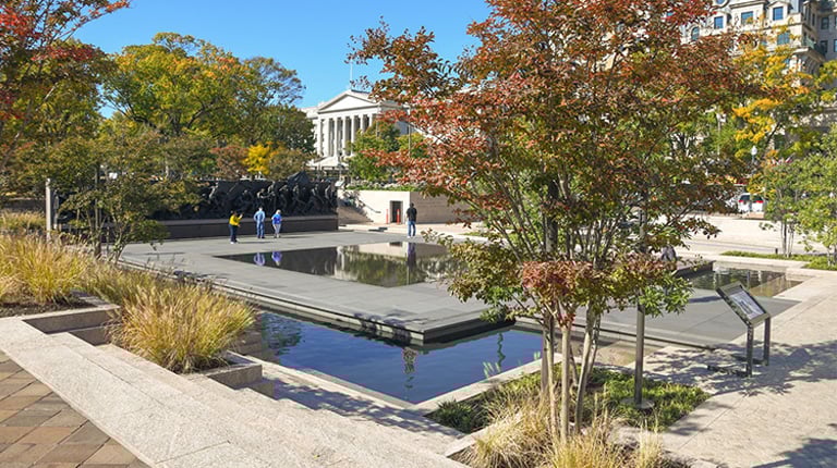 A sculpture of soldiers in an outdoor setting with water and vegetation.
