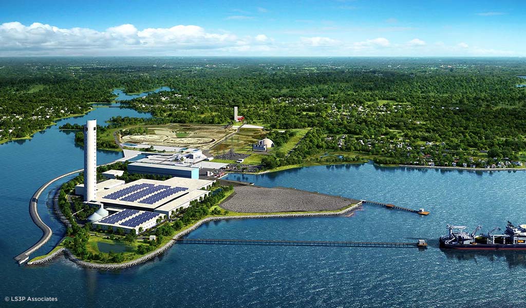 Aerial view of a manufacturing facility situated on a peninsula where a ship is leaving to go out to sea.